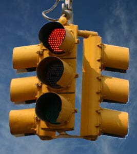 A traffic light with red lights hanging from the side of it.